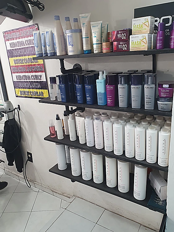 Anaquel de tubo negro con productos profesionales para el cabello y, a un lado, el letrero de alaciados del salón