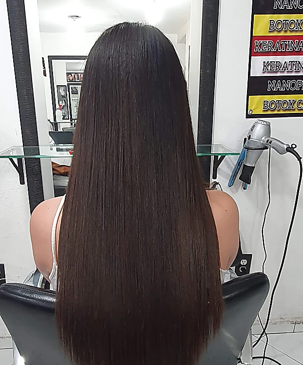 Cabello castaño oscuro muy largo y liso, corte en V, de espaldas en el sillón del salón